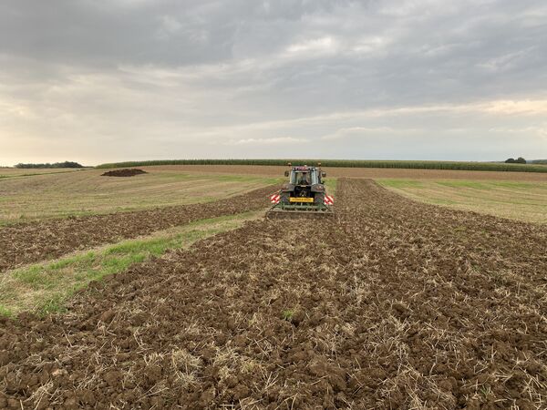 Fendt met cultivator werkt een stoppelveld om onder een bewolkte hemel
