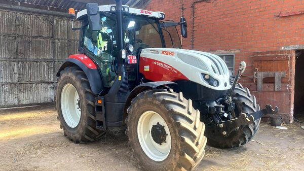 Rood-witte Steyr 4145 Profi Classic met frontkoppeling in een oude schuur
