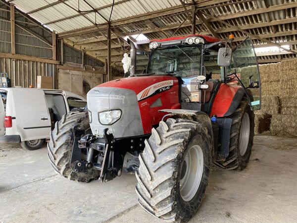 Rode McCormick X10.40 met frontkoppeling in een schuur naast strobalen