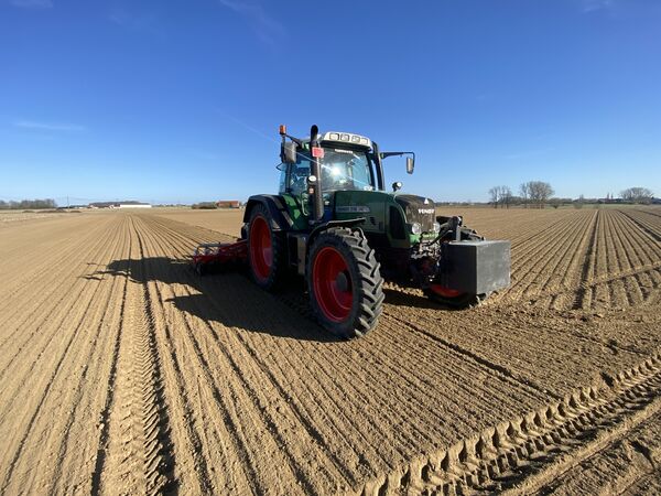 Fendt 718 met rode rotoreg trekt kaarsrechte sporen over een pas bewerkt perceel