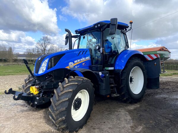 Blauwe New Holland T6.160 met Amazone-kunstmeststrooier op het erf