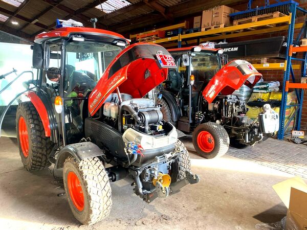 Twee Kubota-compacttractoren met geopende motorkap in de werkplaats tijdens onderhoud