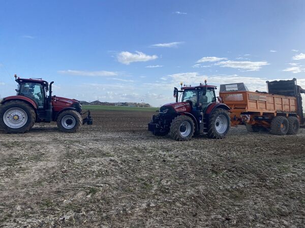 Twee Case IH Puma-tractoren op een akker, één met oranje Dezeure-mestverspreider